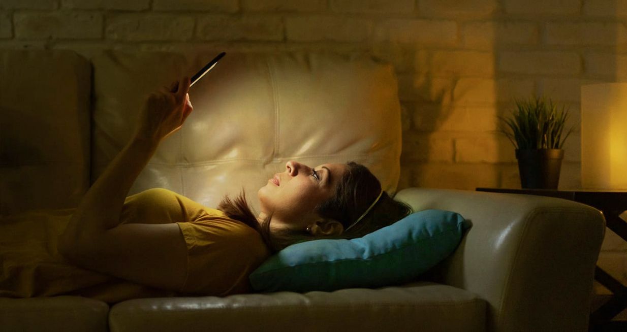 Woman laying on couch reading on Glowlight 4