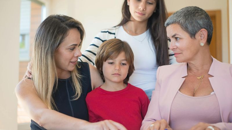 A diverse family discussing financial planning in a modern home office, representing the balance of saving and supporting loved ones abroad.
