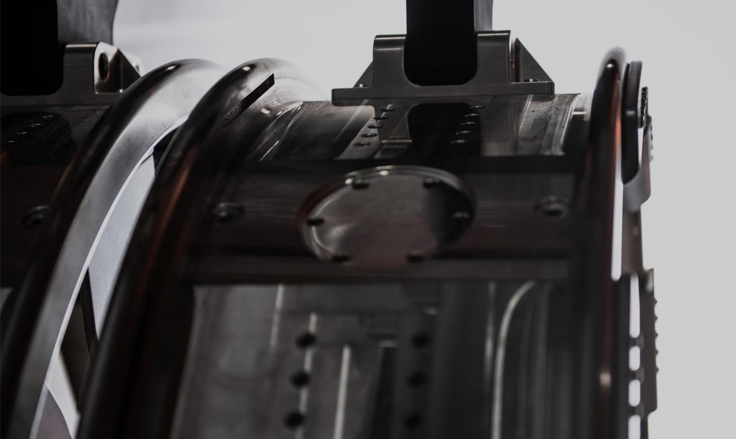 Close-up of dark, polished metal rings and machined support structures from fusion research equipment.