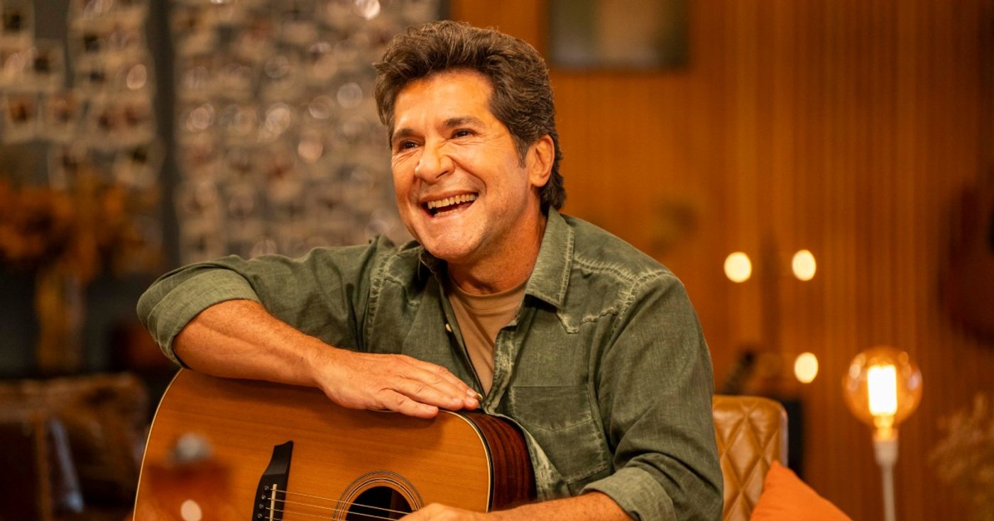 Daniel sorri com um violão no cenário de Viver Sertanejo.