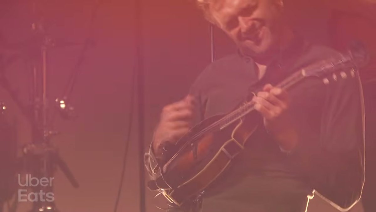 Chris Thile tocando um instrumento de cordas durante a apresentação com Mumford & Sons.
