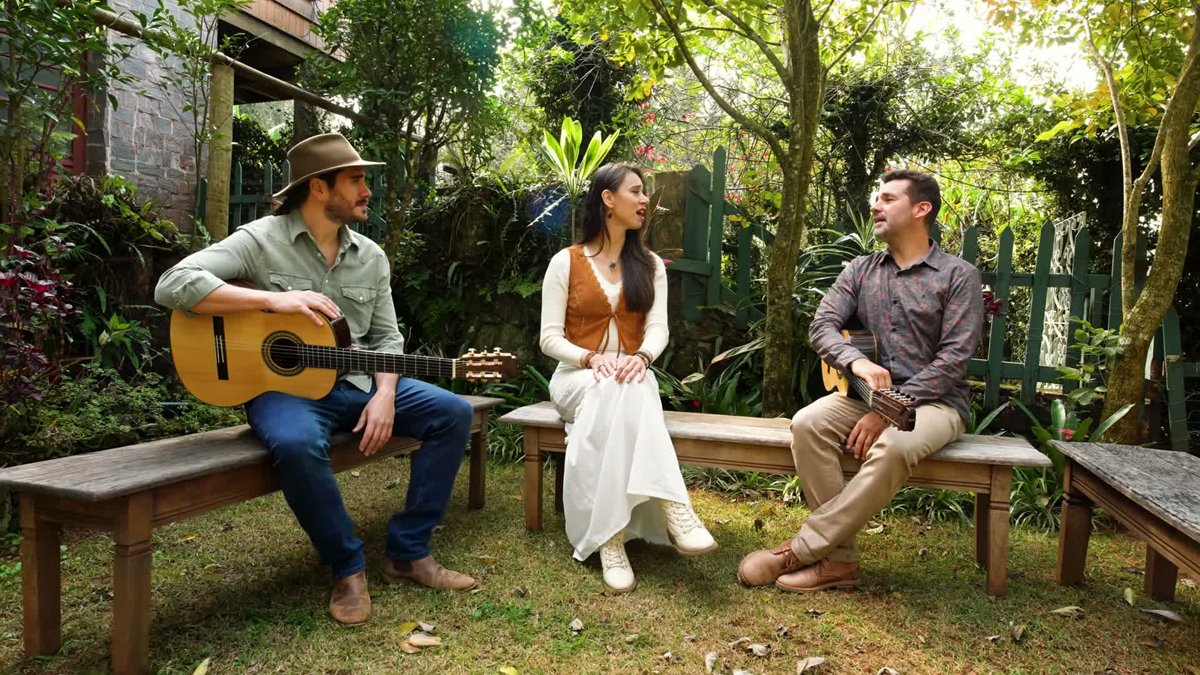 Gabriel Sater e AnieRafa cantam sentados em um jardim no clipe Infância de Interior
