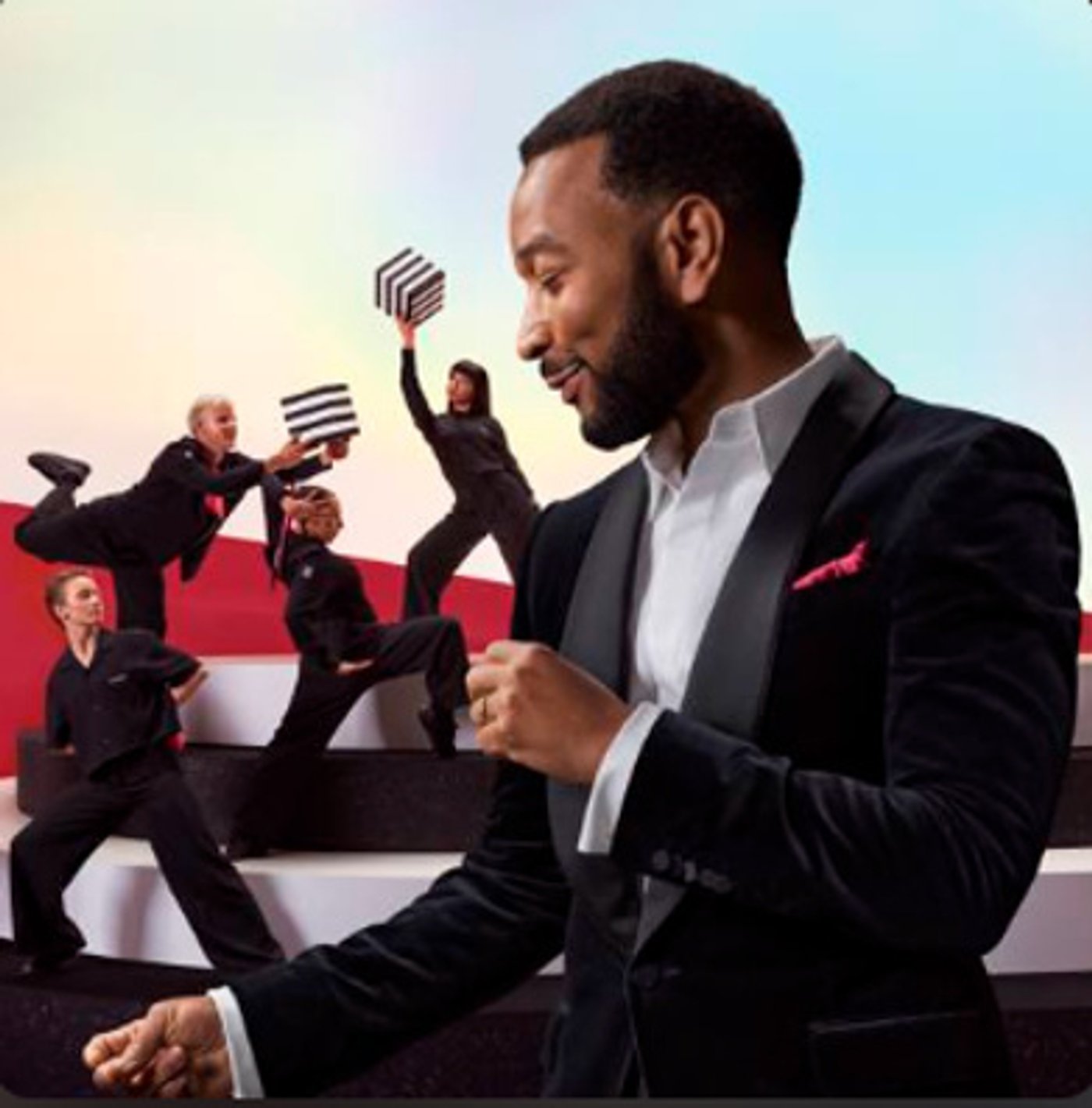John Legend ao piano, com bailarinos ao fundo, em imagem da campanha de fim de ano