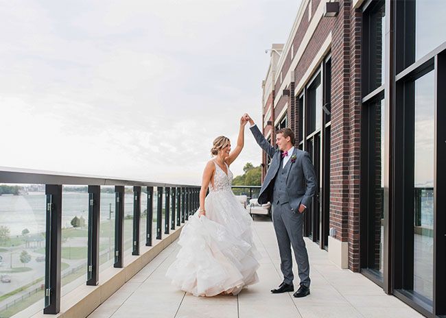 Bride and groom wearing a Generation Tux Iron Gray Suit dancing together on a balcony