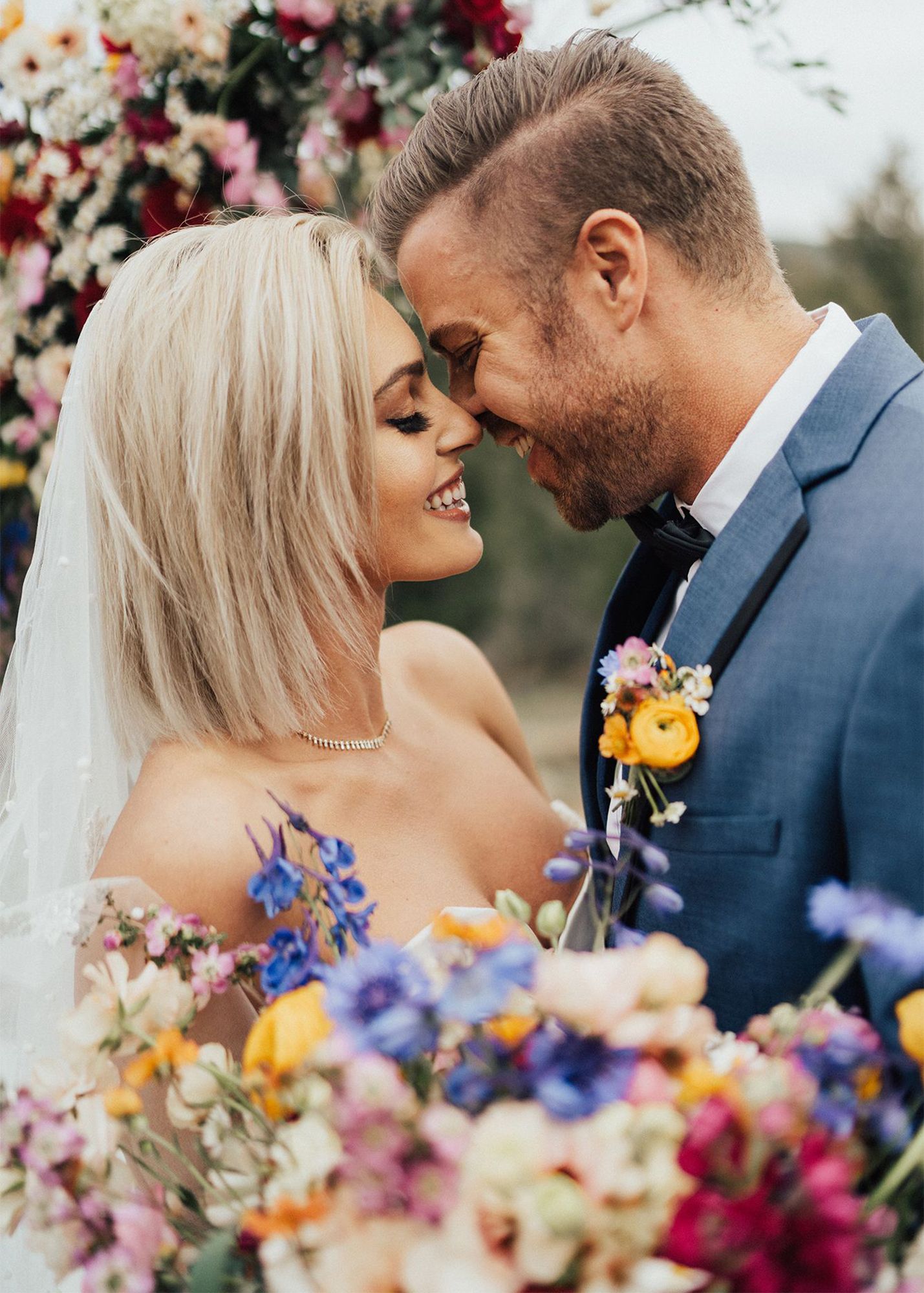 photo of a groom in a blue suit and blonde bride smiling and embracing during wedding ceremony