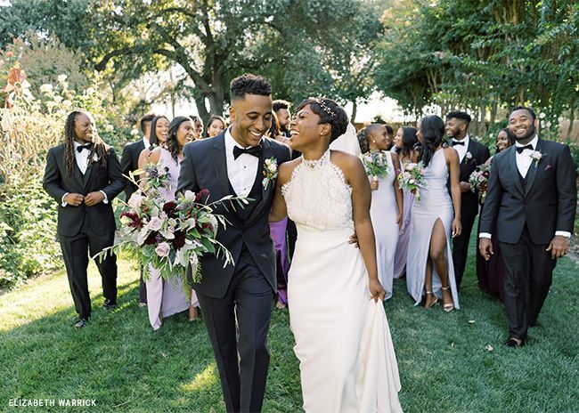 A bride and groom walking in front of the wedding party