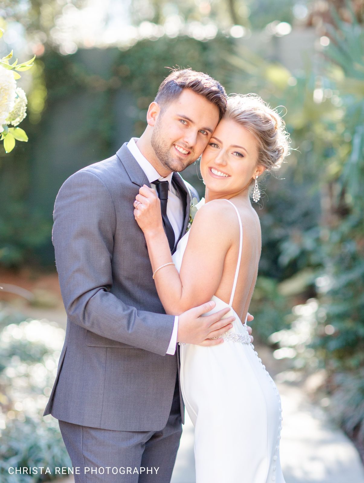 A bride and groom kissing while holding their dogs