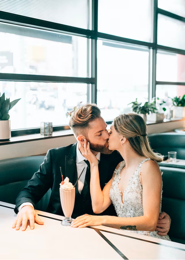 A bride and groom kissing in a diner