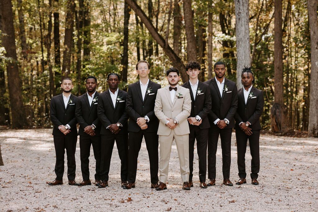 Groom in tan suit and groomsmen in black suits