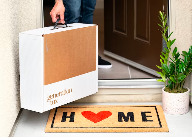 A person picking up a gen tux box from their doorstep