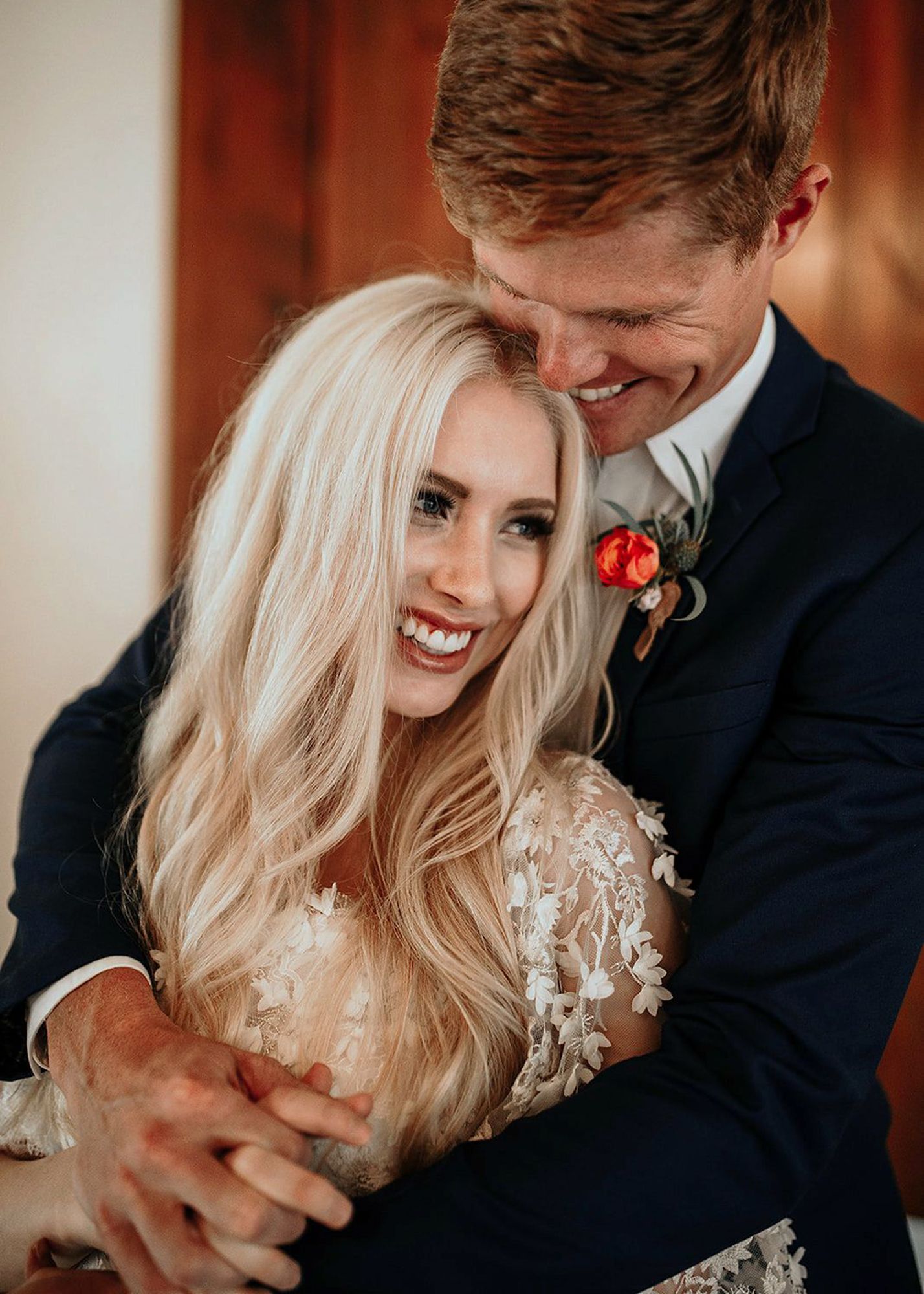 photo of a groom wearing a black tuxedo holding his blonde bride