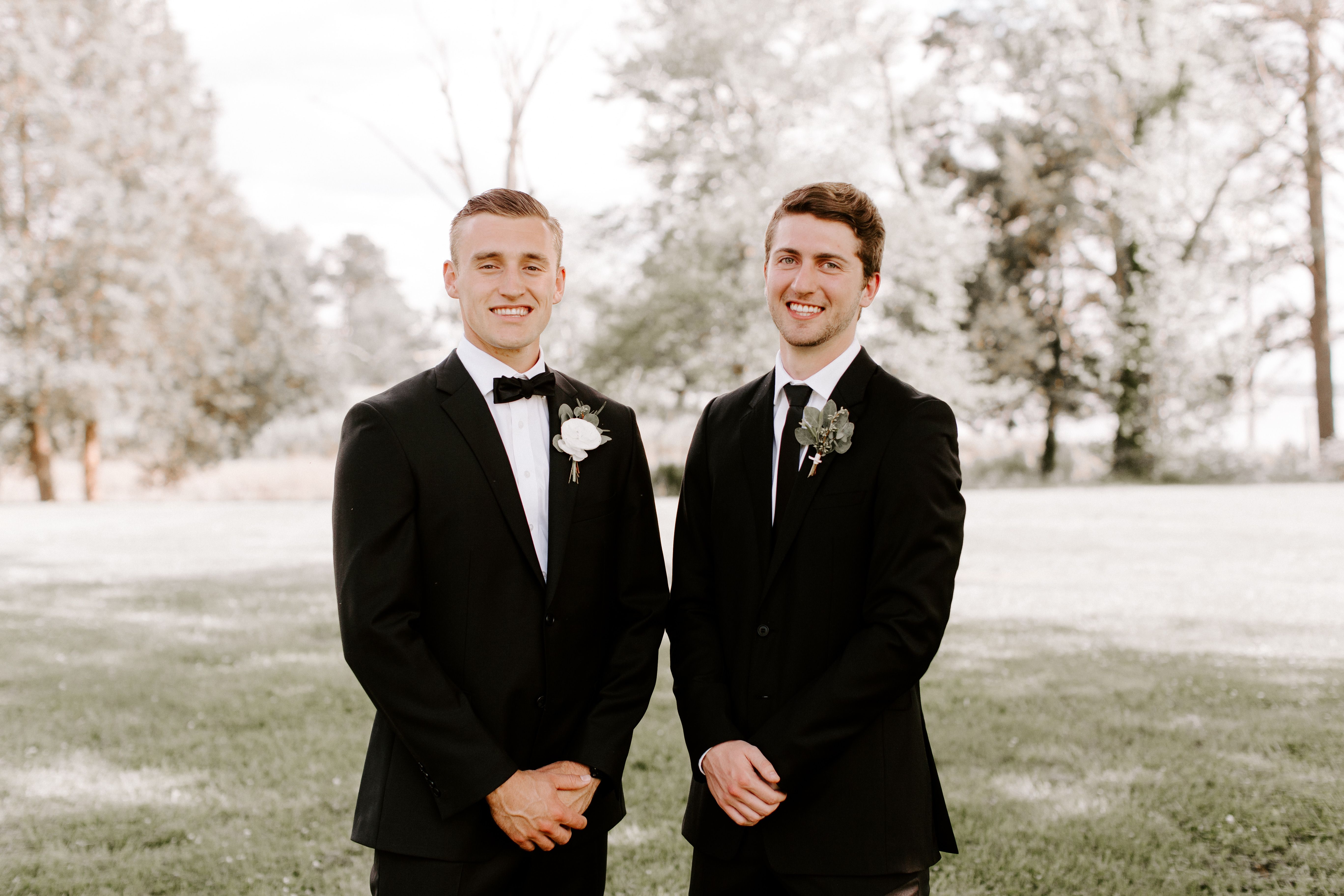 Groom in black tuxedo and groomsmen in black suit 