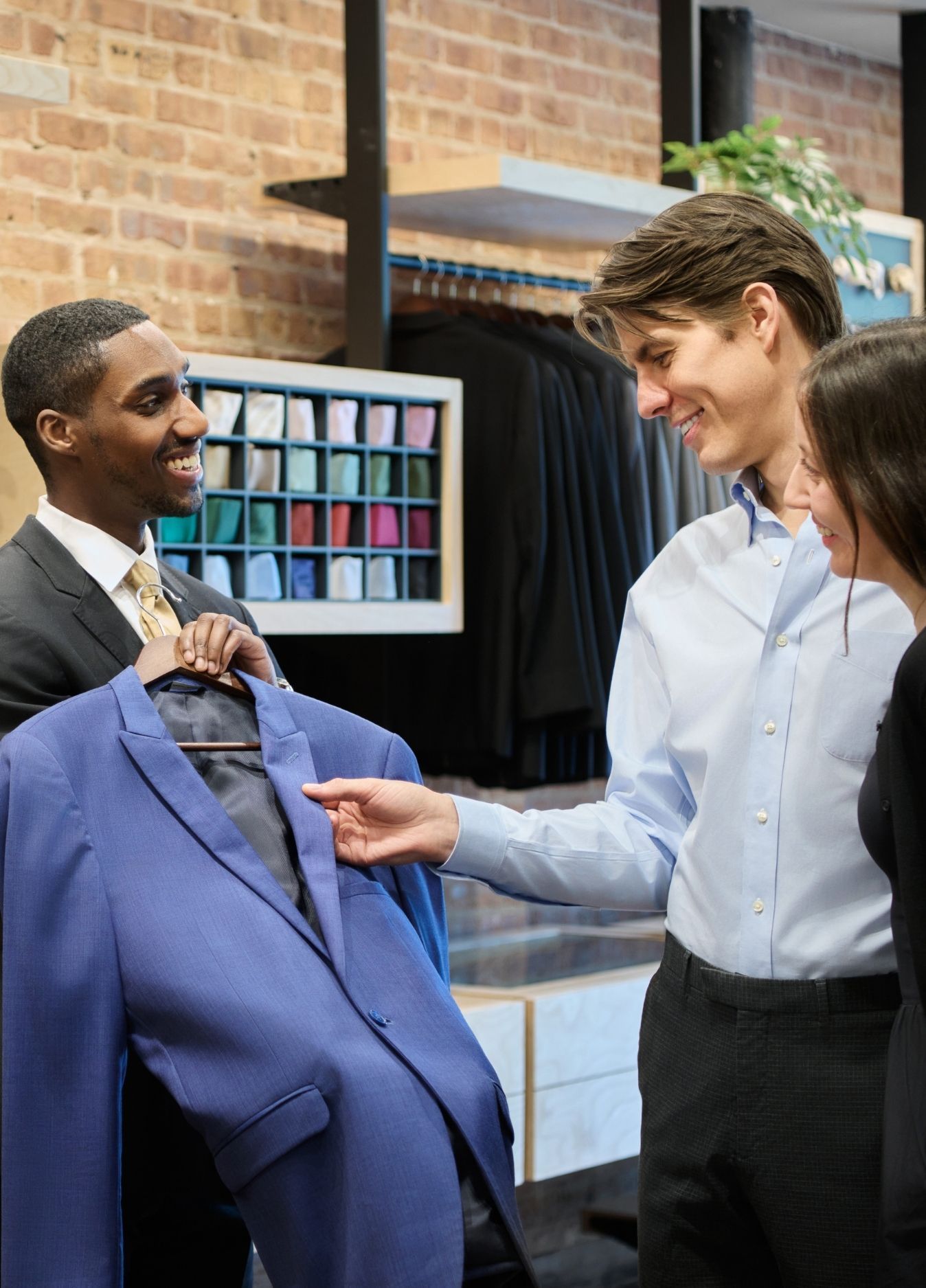 Couple looking at a suit jacket with Generation Tux staff member