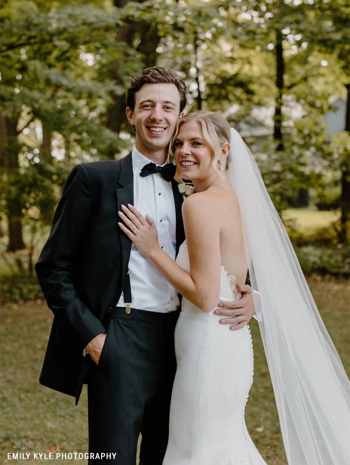 Groom wearing a black tuxedo and suspenders from Generation Tux in nature venue