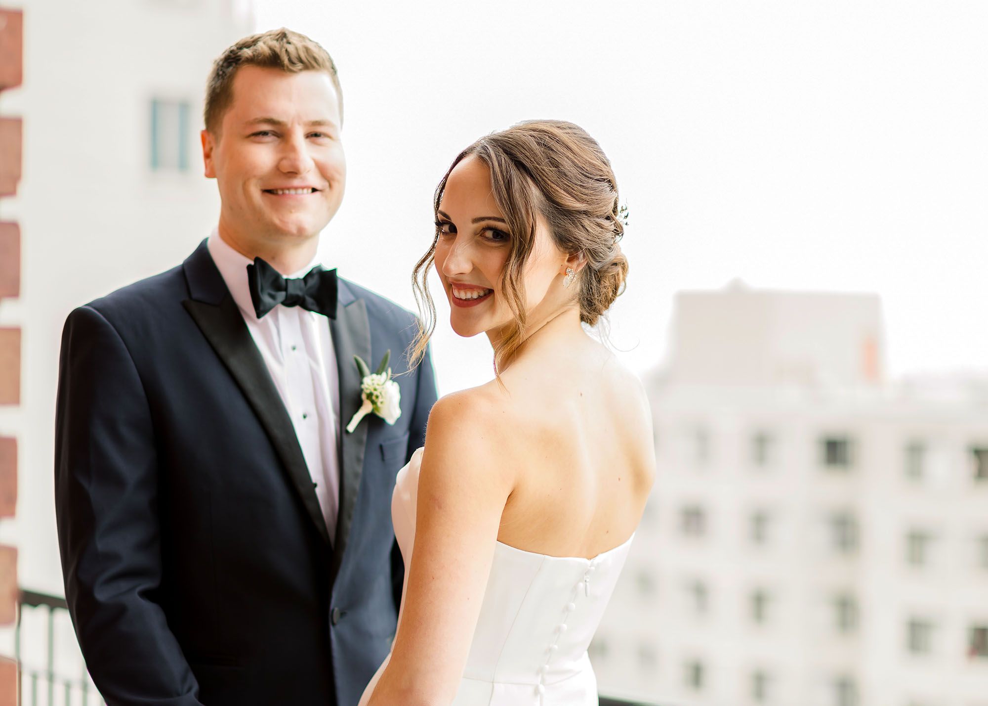 Bride in a strapless gown and groom in a Midnight Blue Peak Lapel Tuxedo on a rooftop