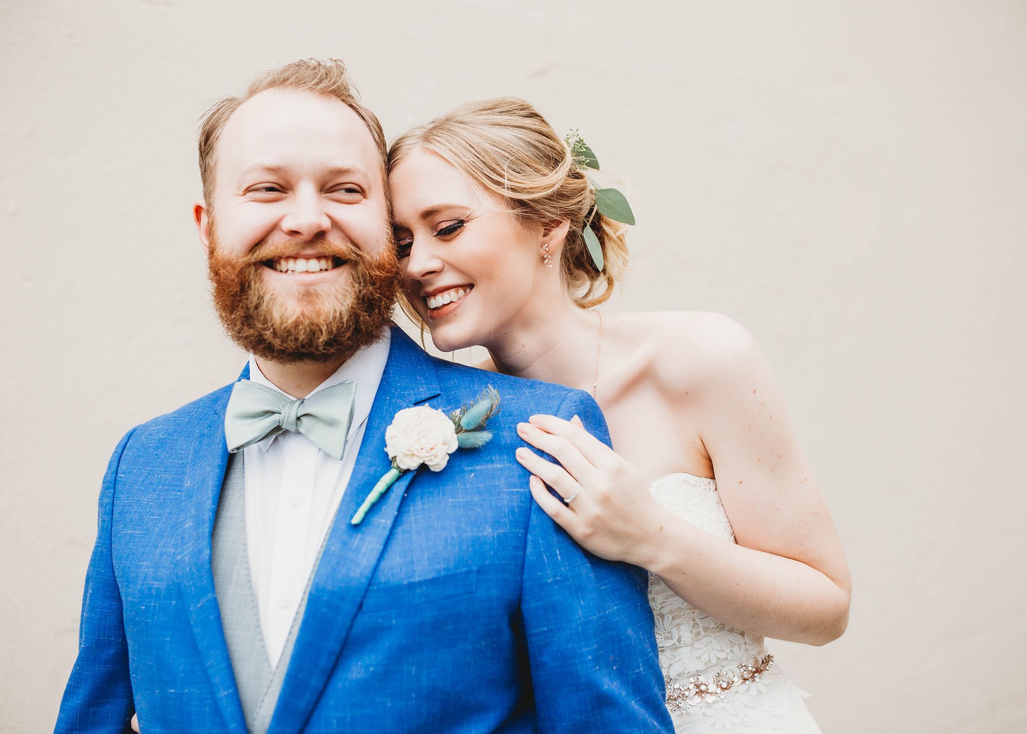Smiling bride and groom wearing blue suit.