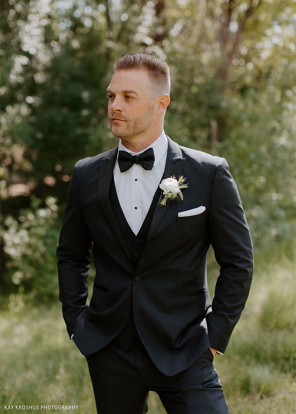  A man standing in a black tuxedo in a field 