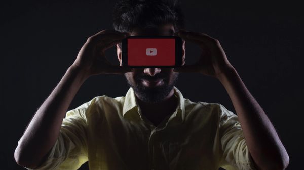 Man holding smartphone with YouTube logo