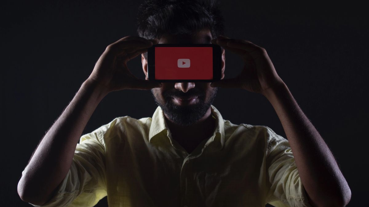 Man holding smartphone with YouTube logo