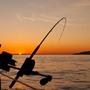 black fishing rod and body of water during golden hour