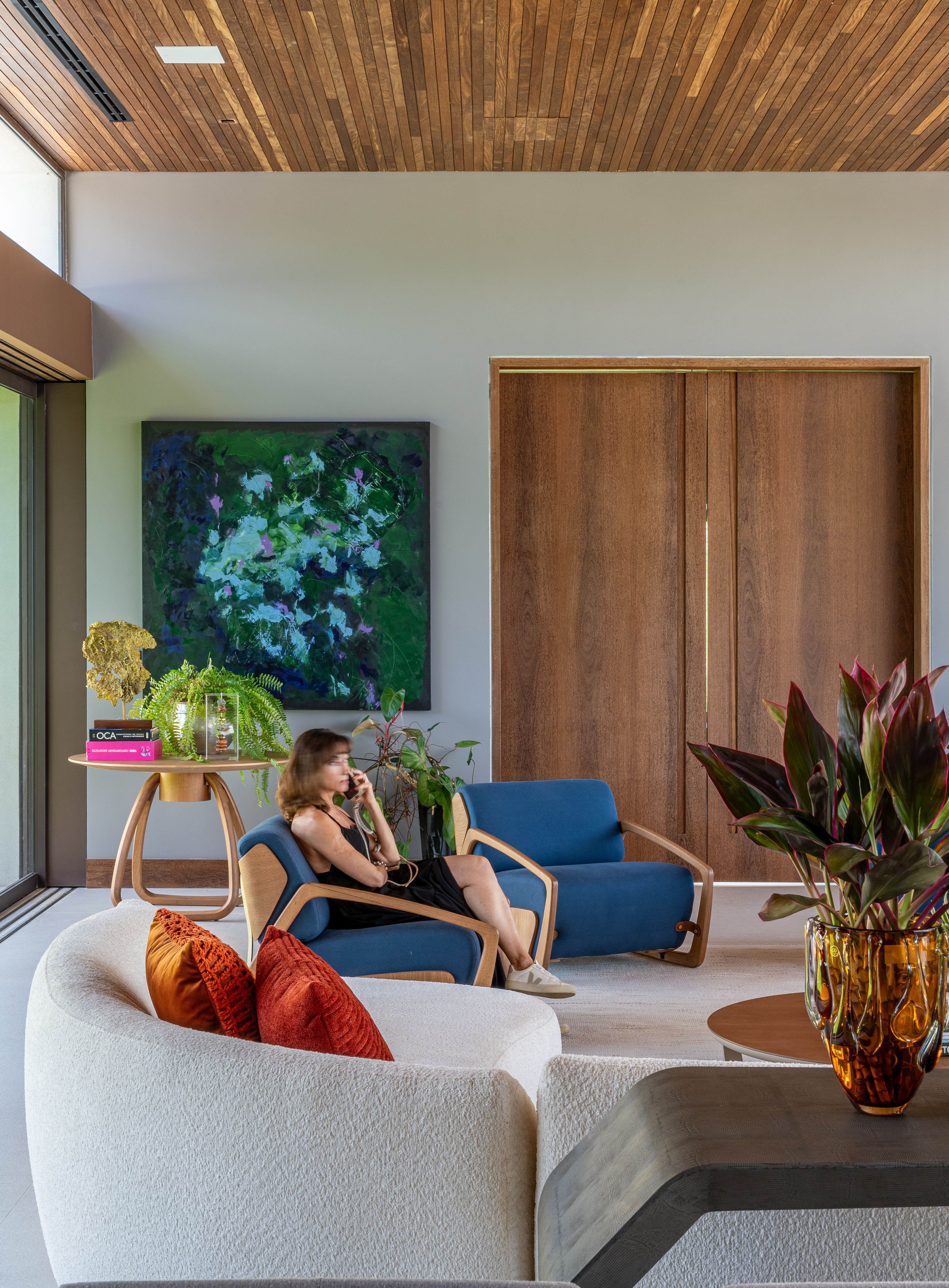 Sala de estar da Residência SCA com forro de madeira, poltronas azuis e obra de arte