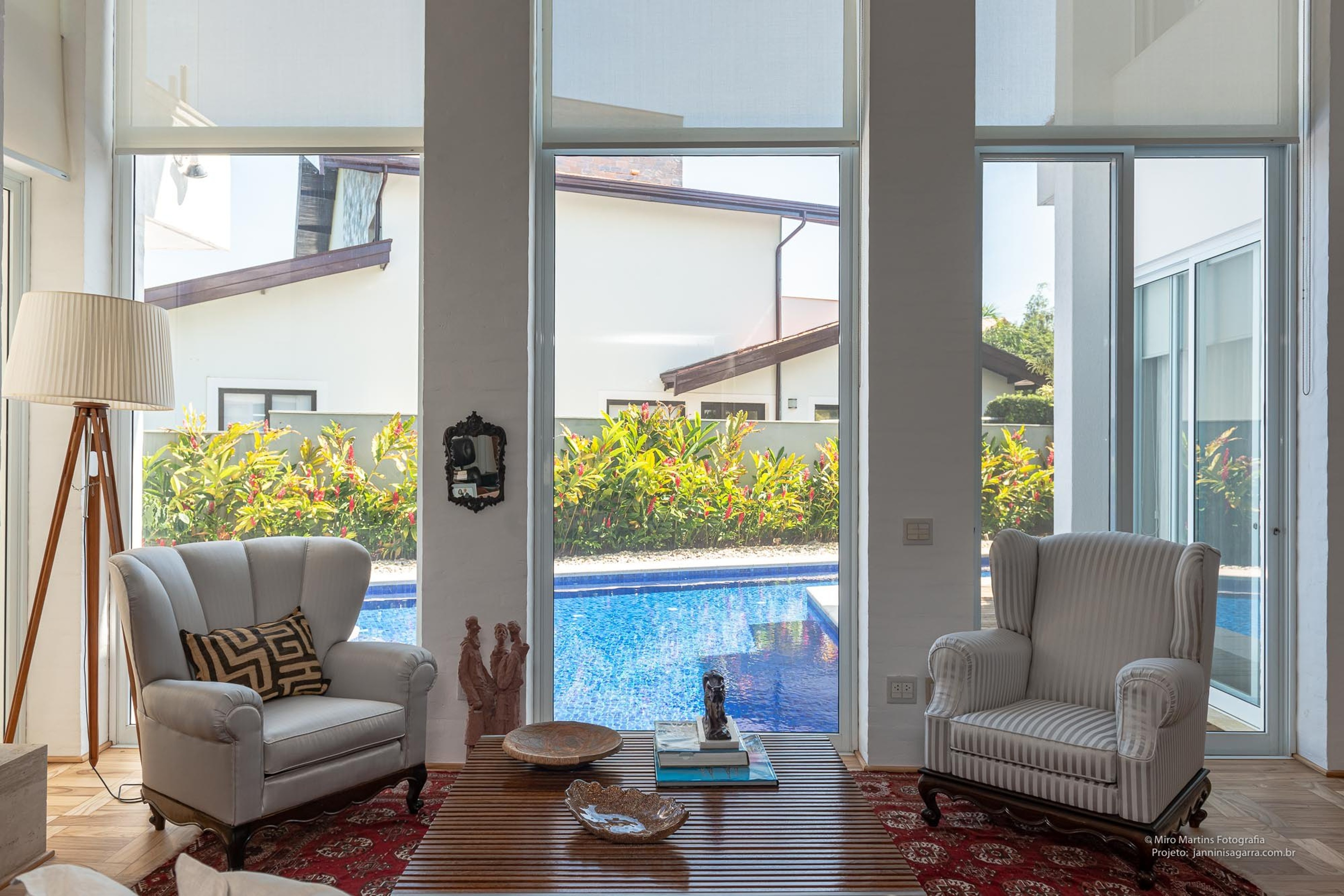 Residência AAA — Poltronas da sala com vista para piscina