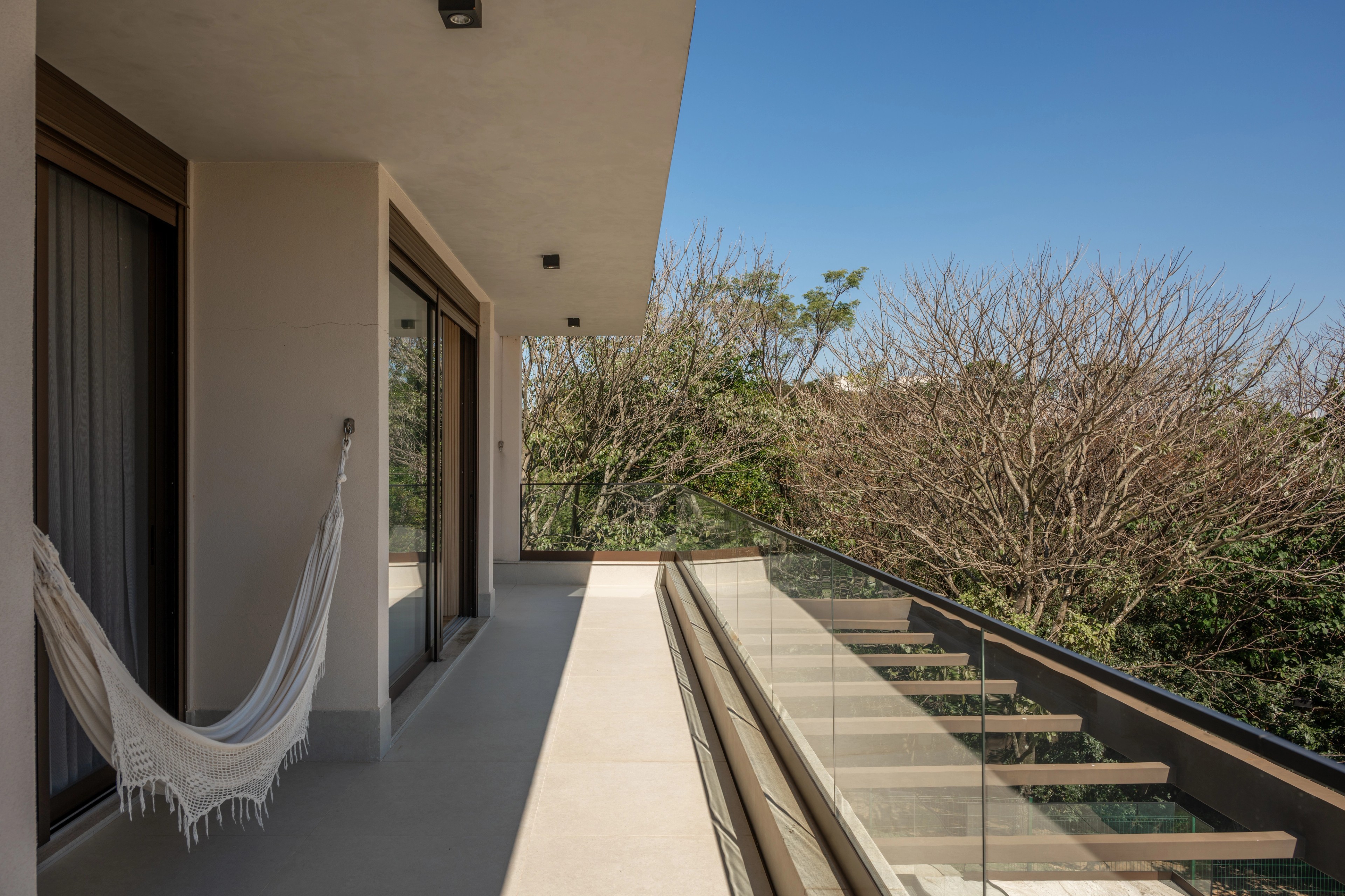Residência SMI — Varanda superior com rede e vista para o jardim