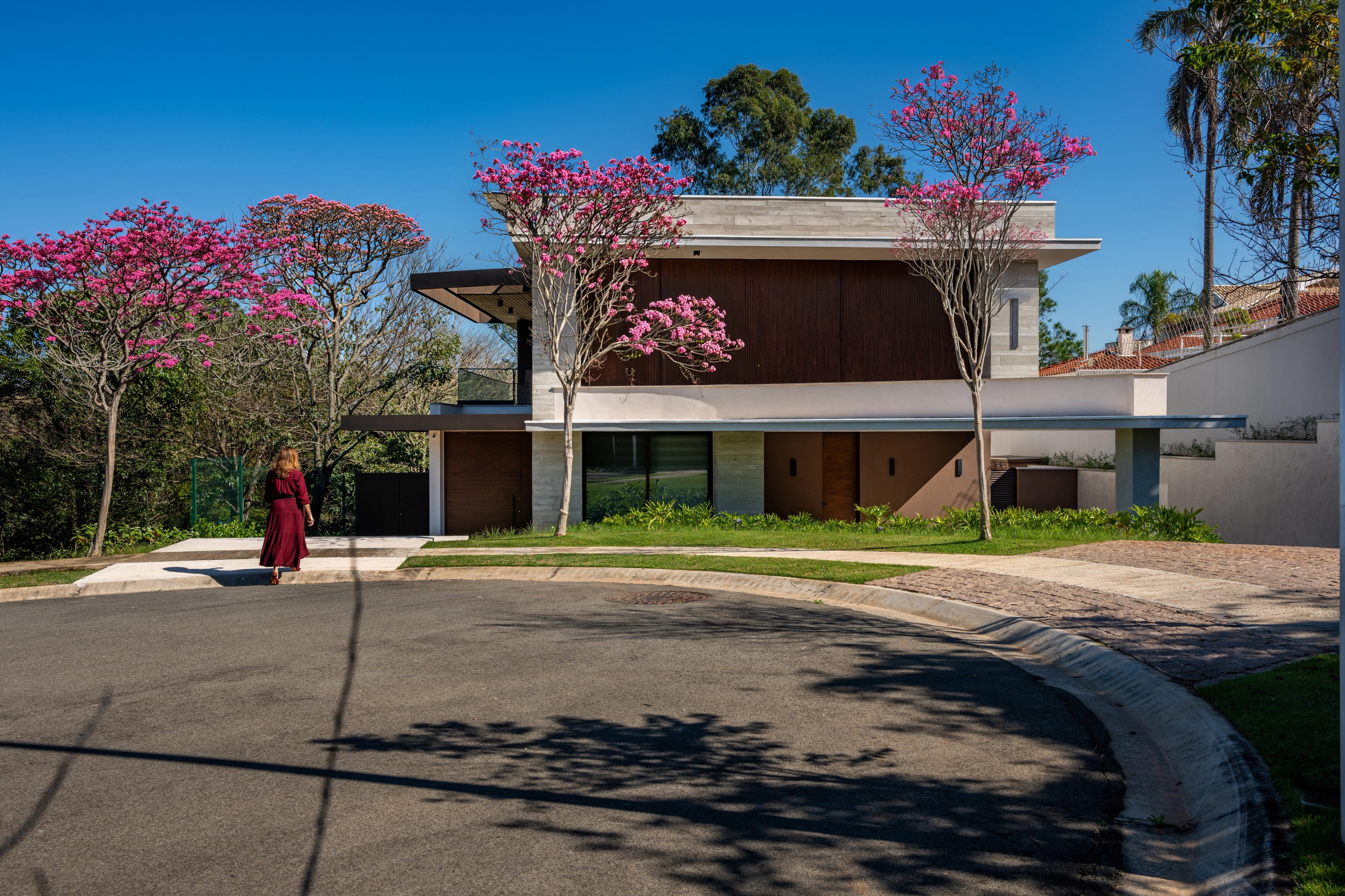Residência SMI — Fachada frontal vista da rua com jardim e árvore florida