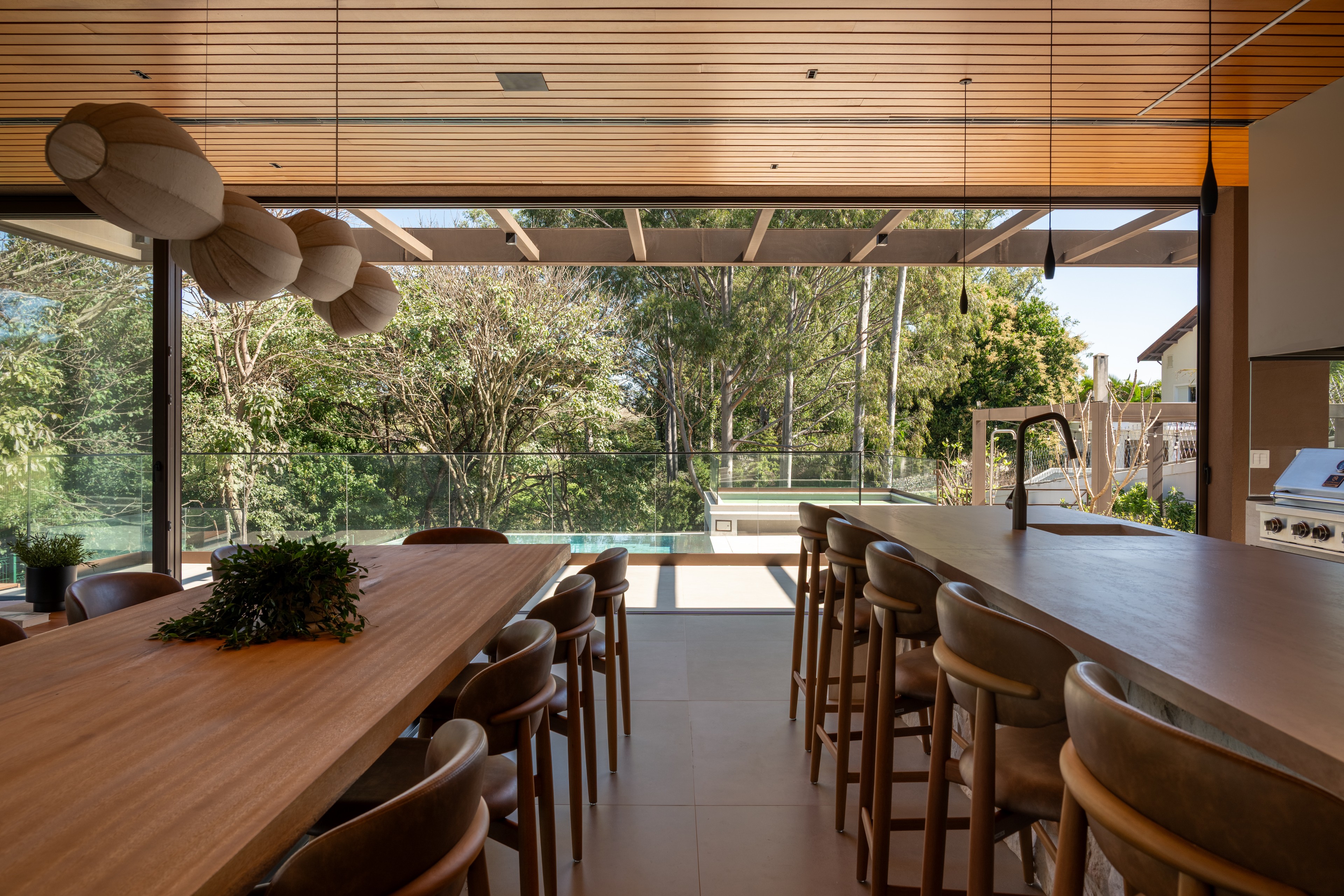 Residência SMI — Mesa e bancada da área gourmet voltadas ao jardim