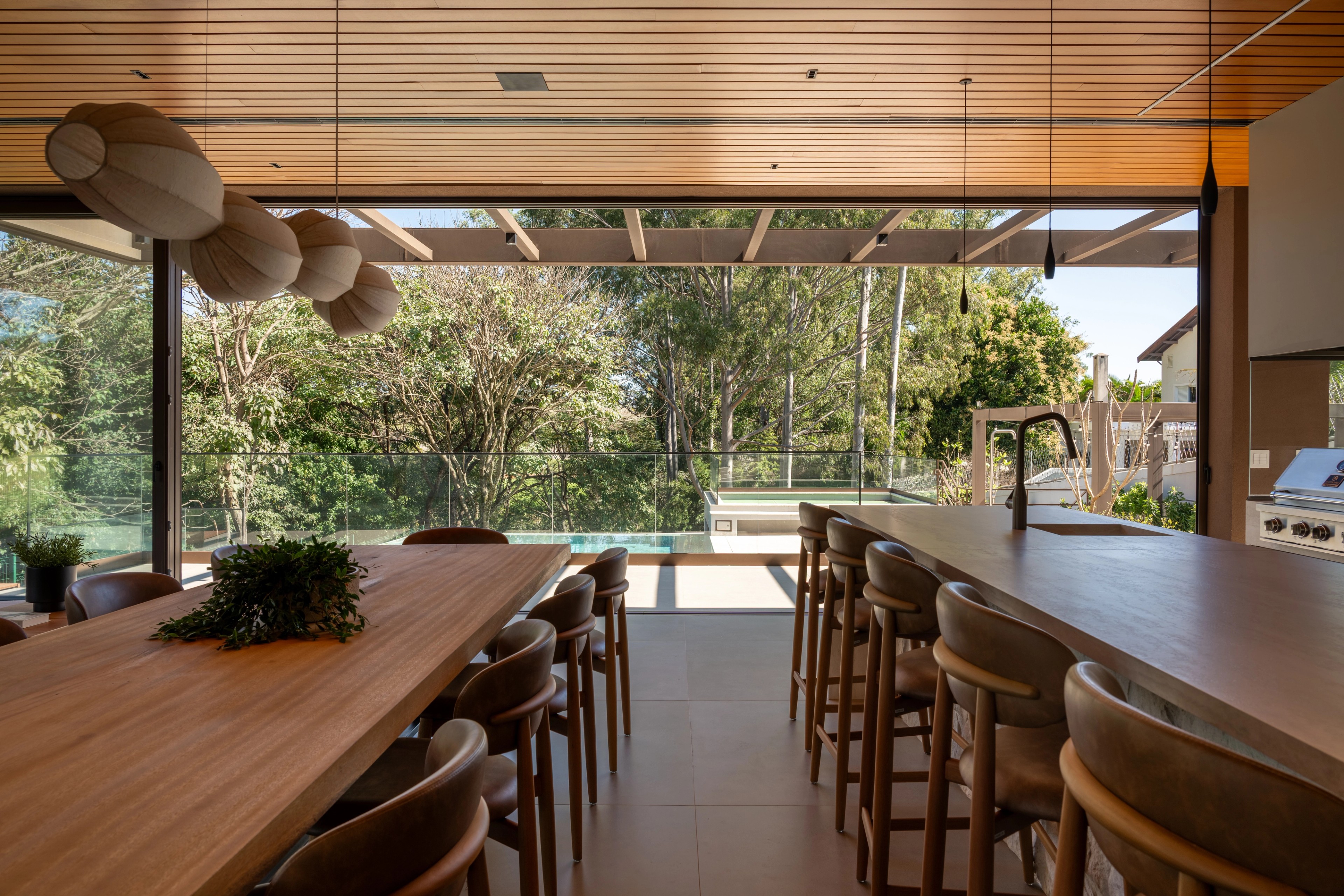 Residência SMI — Mesa e bancada da área gourmet voltadas ao jardim