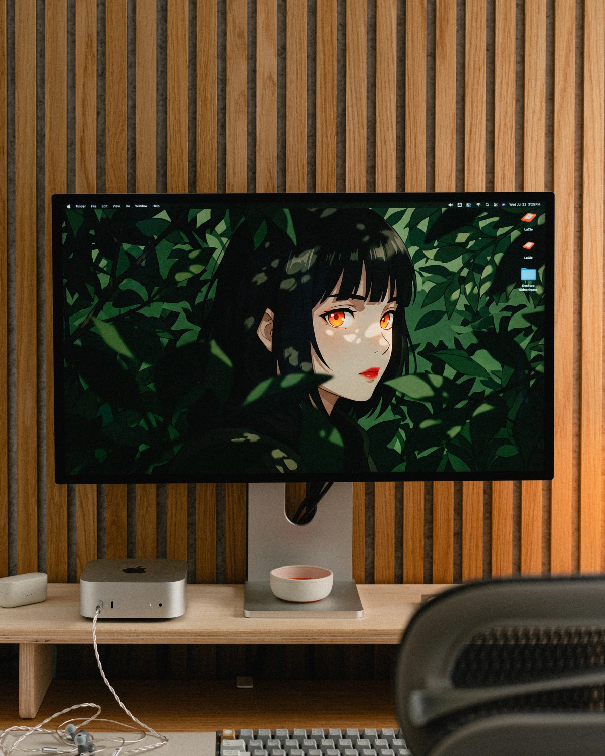 The desk with an illustration of a figure among green leaves on the monitor, and a white keyboard below.
