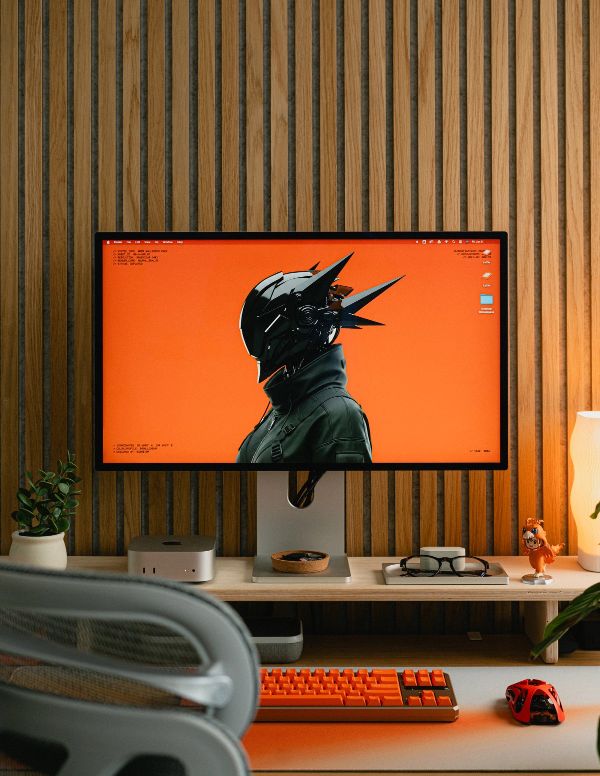 The desk head-on, with the monitor centered above a Mac Mini, a glasses tray and a warm table lamp.