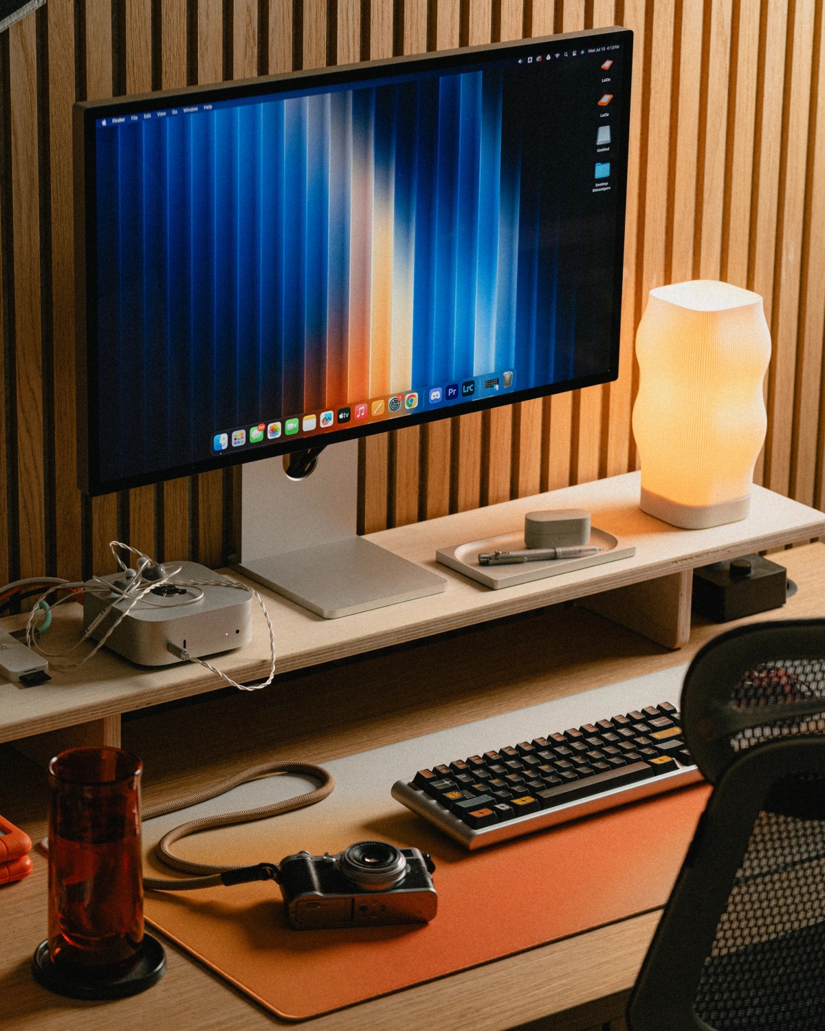 The desk in an earlier arrangement, with a black keyboard, a compact camera and an orange deskpad.