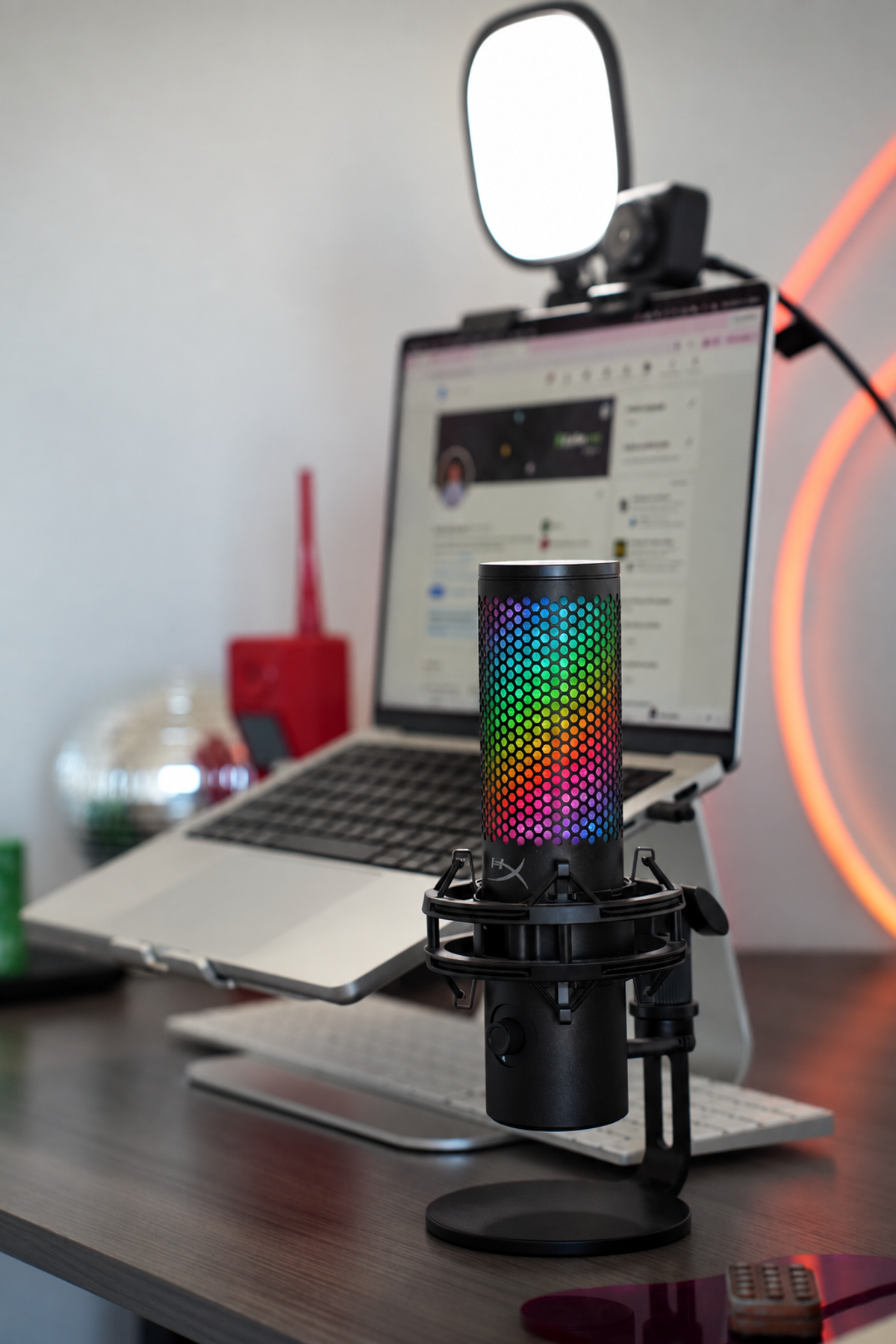 Close-up of the HyperX QuadCast microphone on its shock mount, backlit by an orange neon rope light