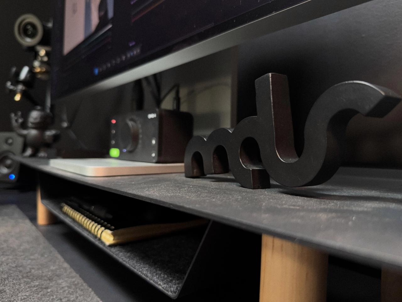Black mds letter sculpture on a desk shelf in front of an audio interface