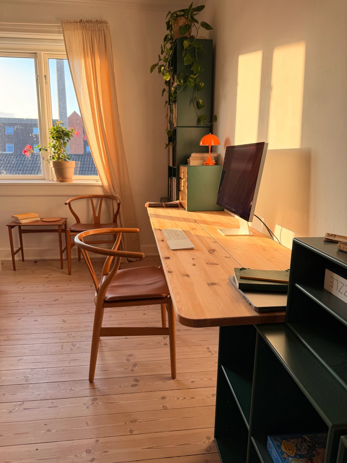Copenhagen home office with a pine desk, Apple Studio Display, green Montana cabinets and Panthella lamps
