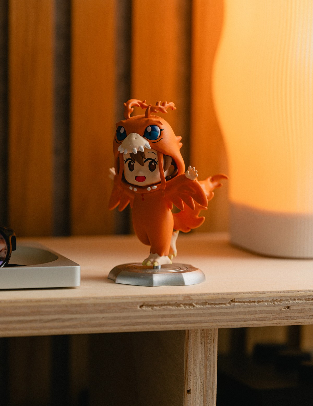 A small orange Digimon figure on the shelf beside a glowing lamp.