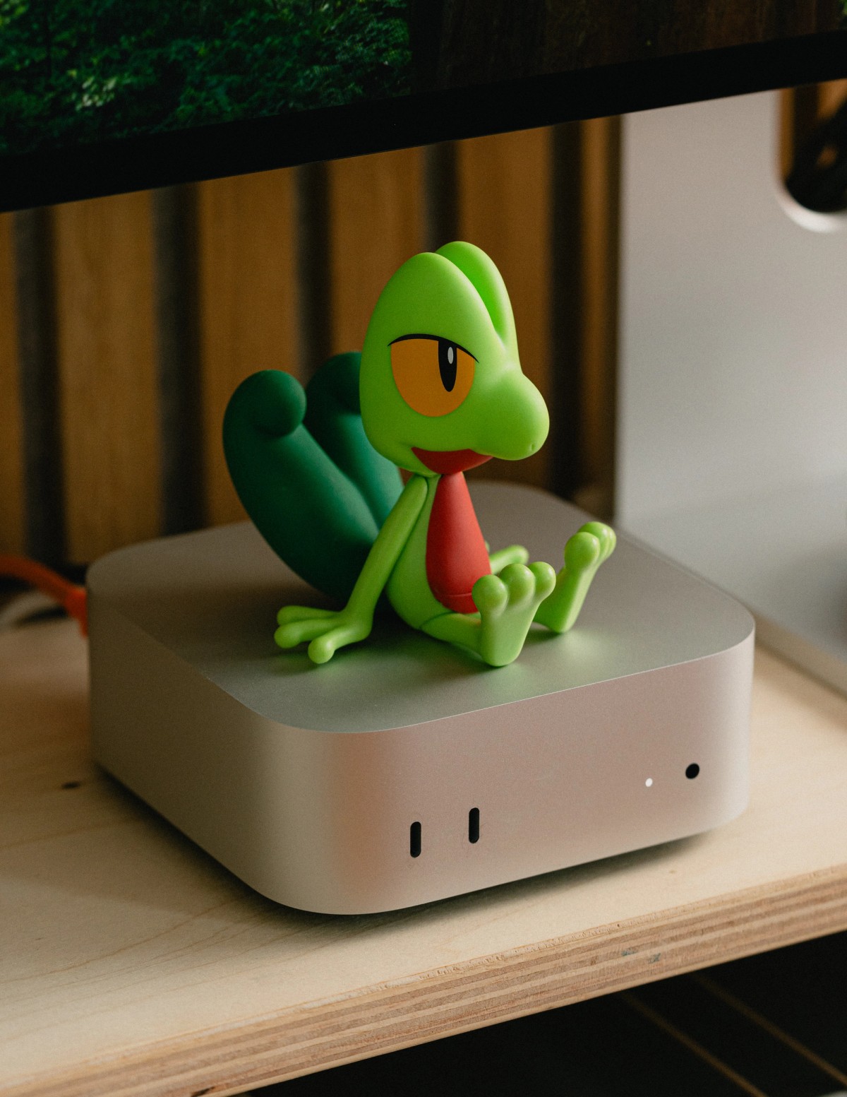 A green Treecko figure sitting on top of a silver Mac Mini.