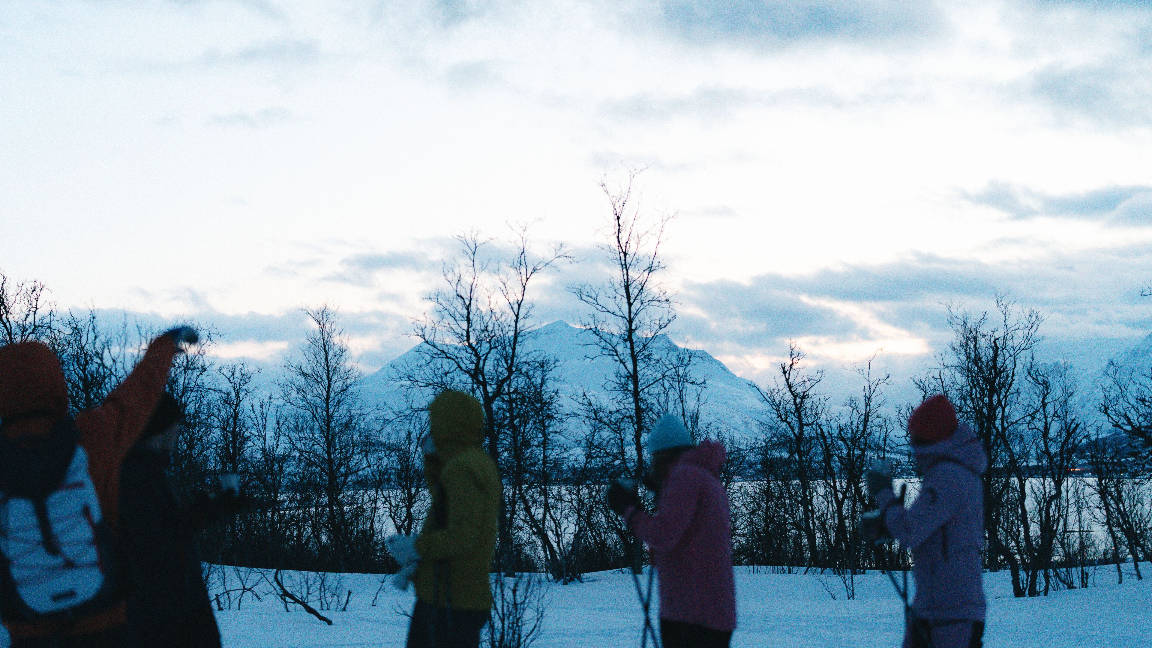 Tourists testing skis in Tromsø with mountains and sun in the background