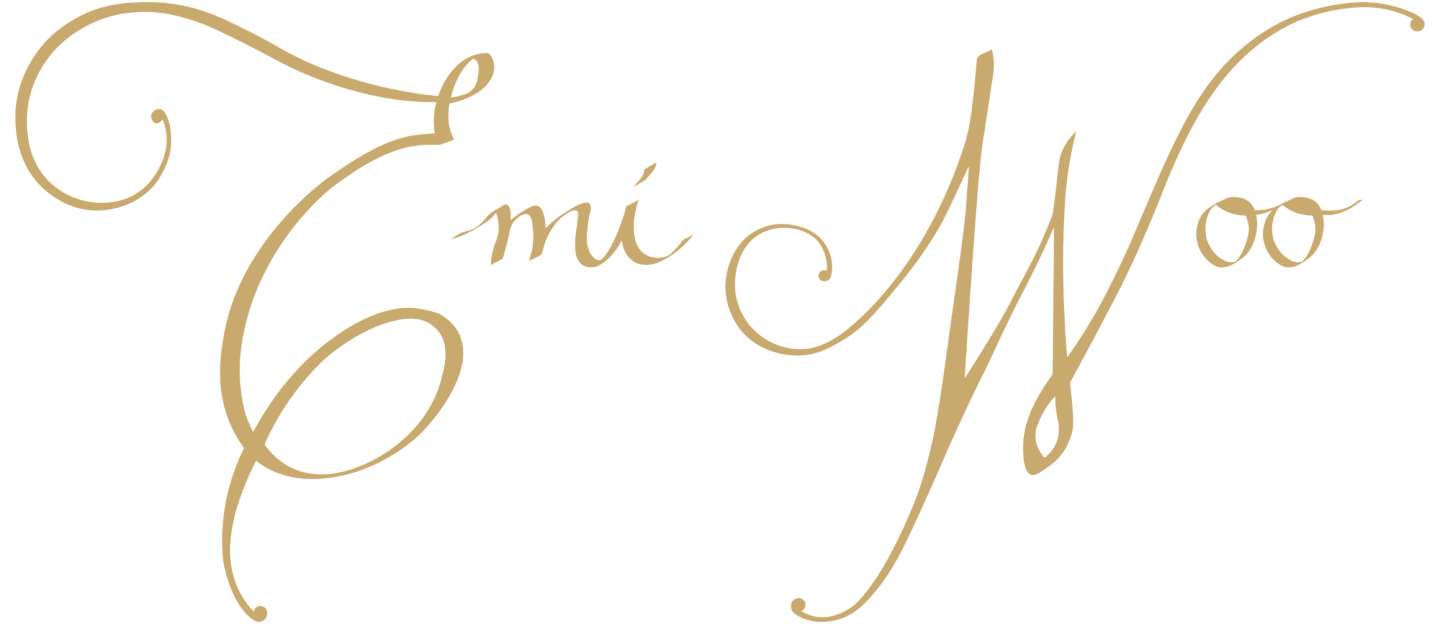 Emi Woo — the house's wordmark, handwritten in flowing champagne-gold calligraphy with ornate capital E and W
