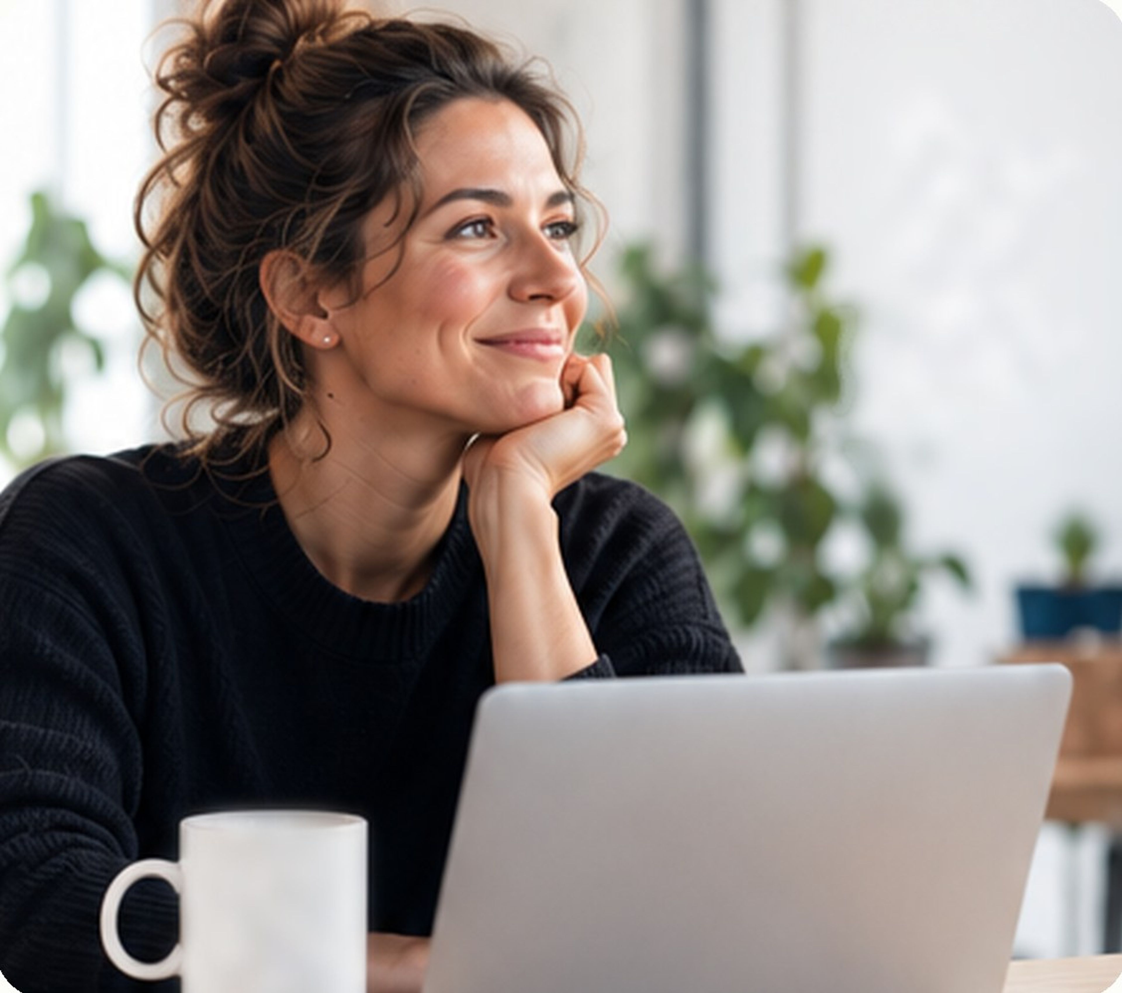 A woman looking up from her laptop, smiling