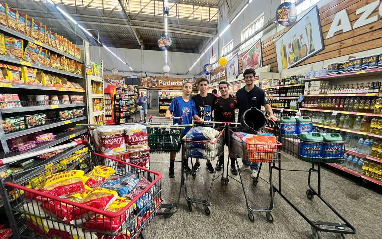 Estudantes posam com carrinhos cheios de alimentos e produtos para a ação solidária em Juiz de Fora