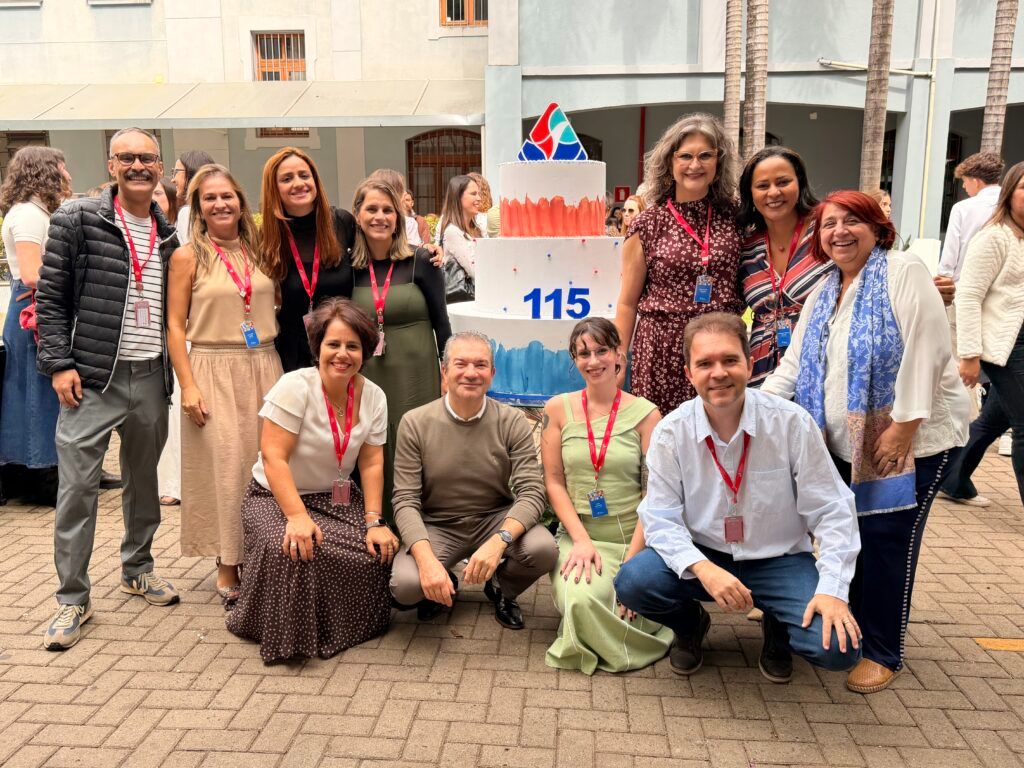 Representantes da Rede reunidos diante do bolo comemorativo dos 115 anos do Colégio Sagrado Coração de Jesus
