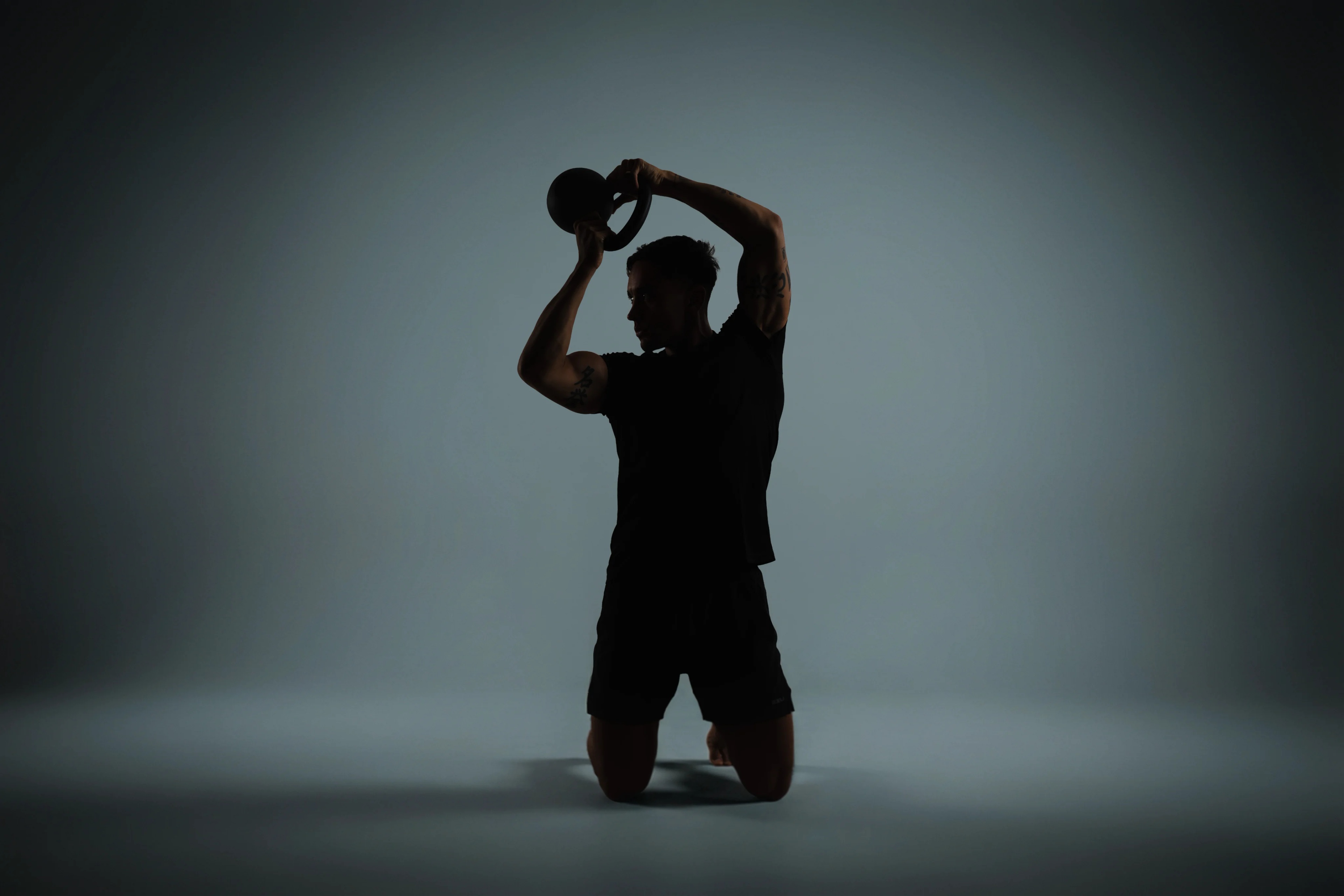 man lifting a kettlebell over head