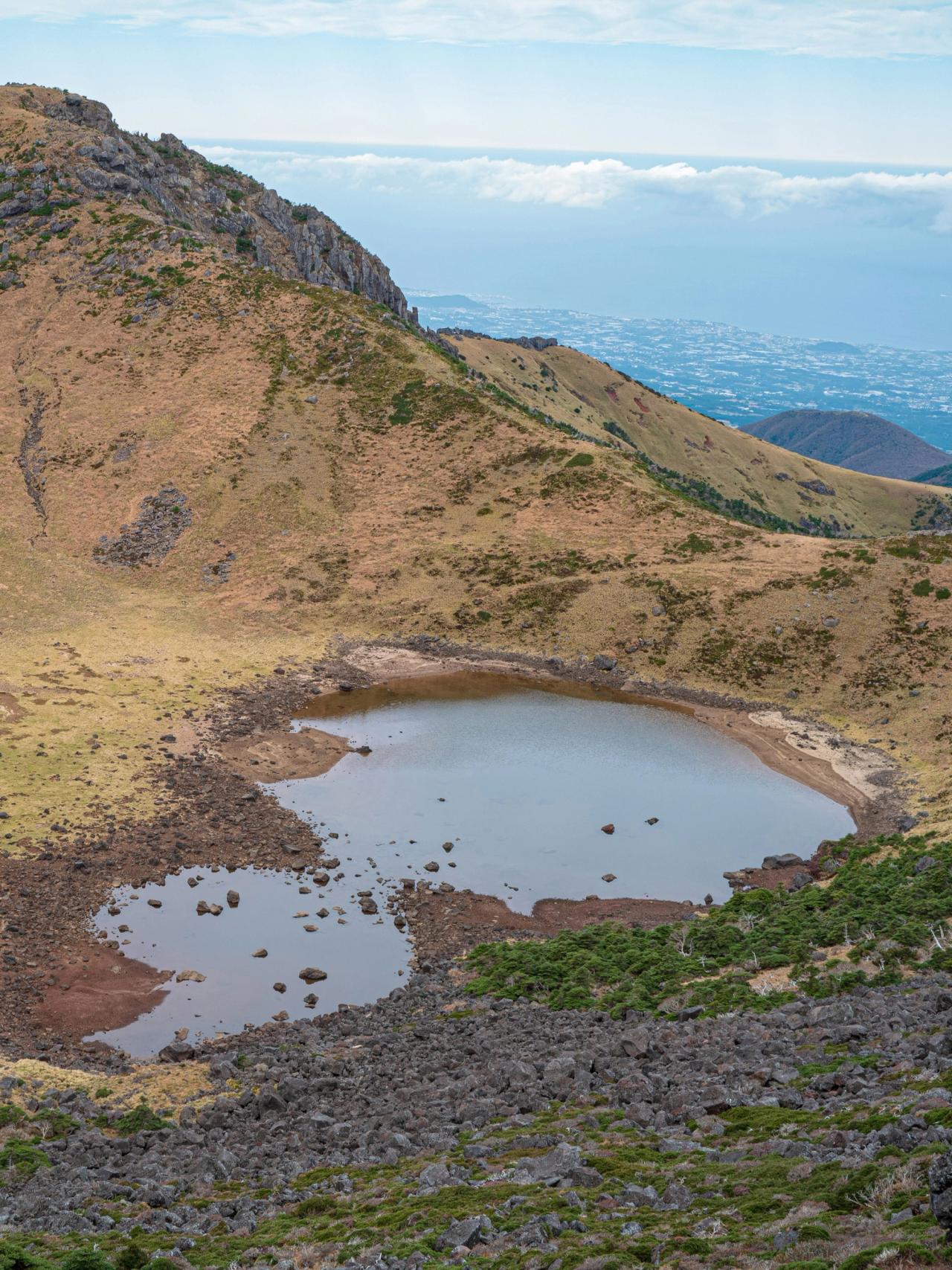 Baengnokdam crater lake in the Hallasan summit caldera, with Jeju's coastline beyond