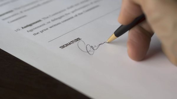 A hand signing financial paperwork