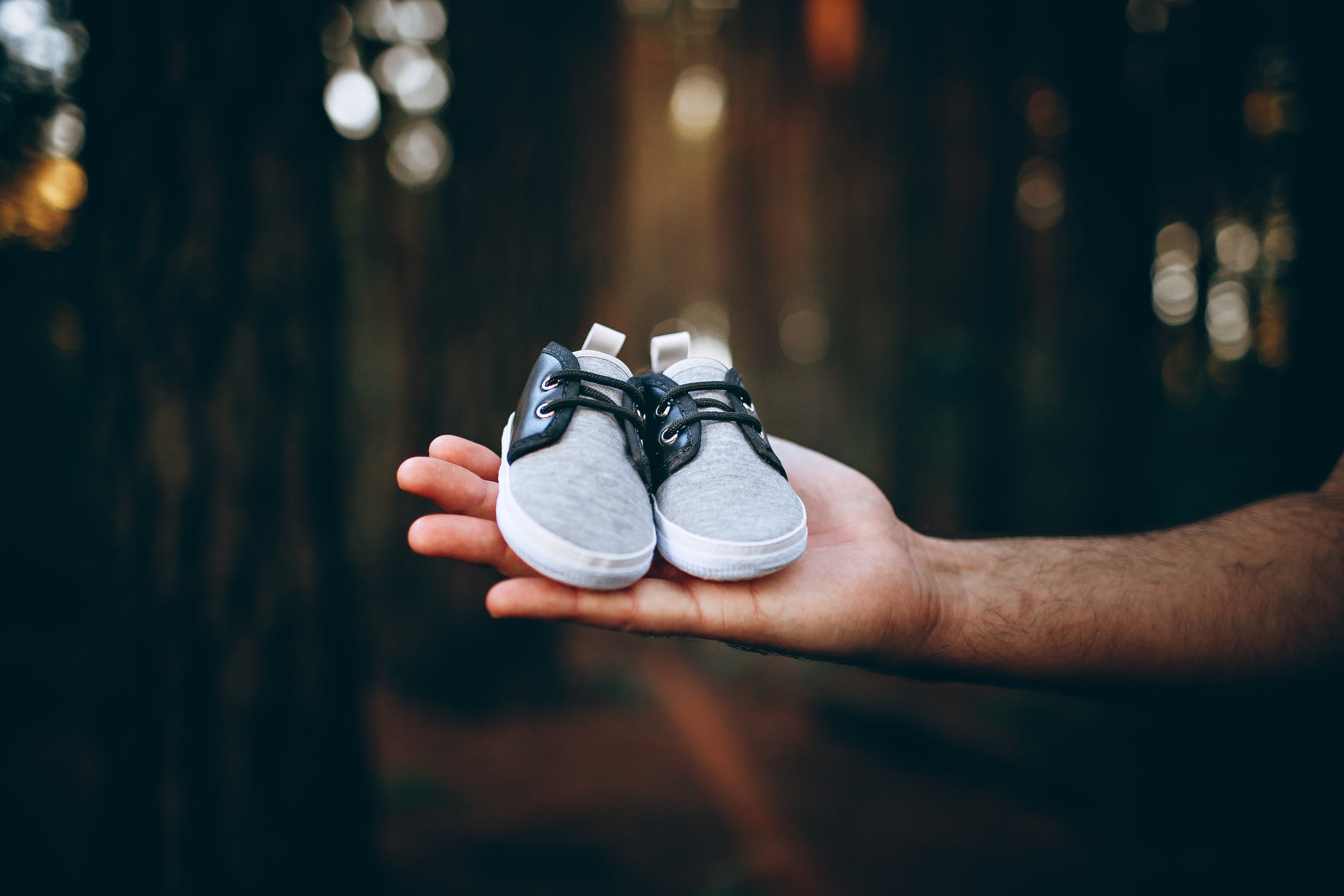 a hand holding a pair of baby shoes