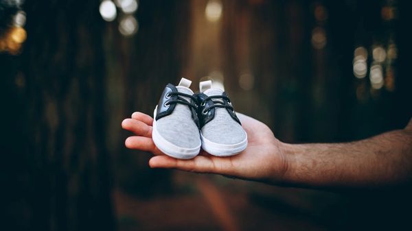 a hand holding a pair of baby shoes