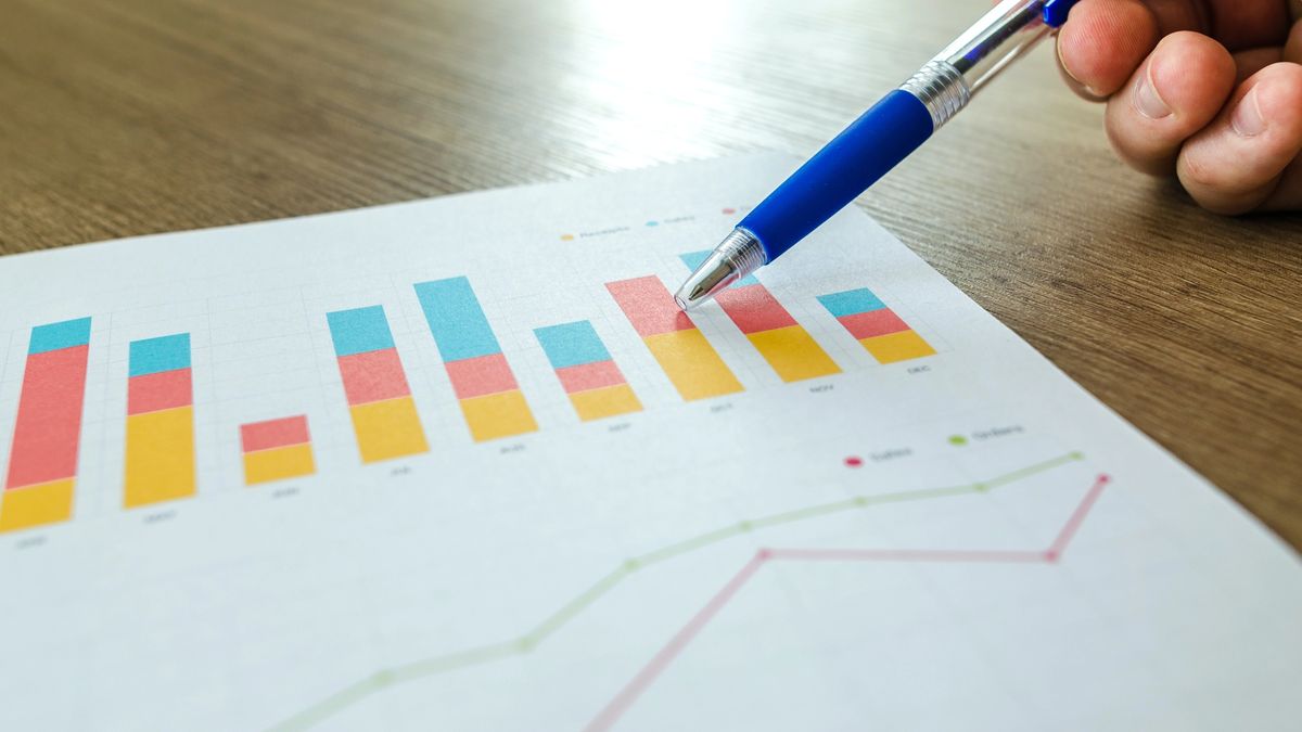 Person Holding Pen Pointing at Graph