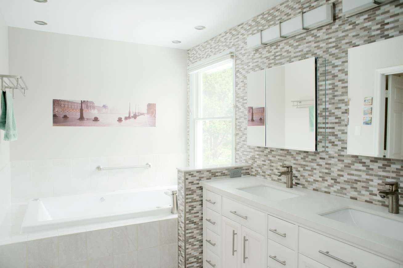 Contemporary Master Bath renvoation in Clarksville, MD with his and hers vanity, deep soaking tub and modern stainless steel fixture and lighting design